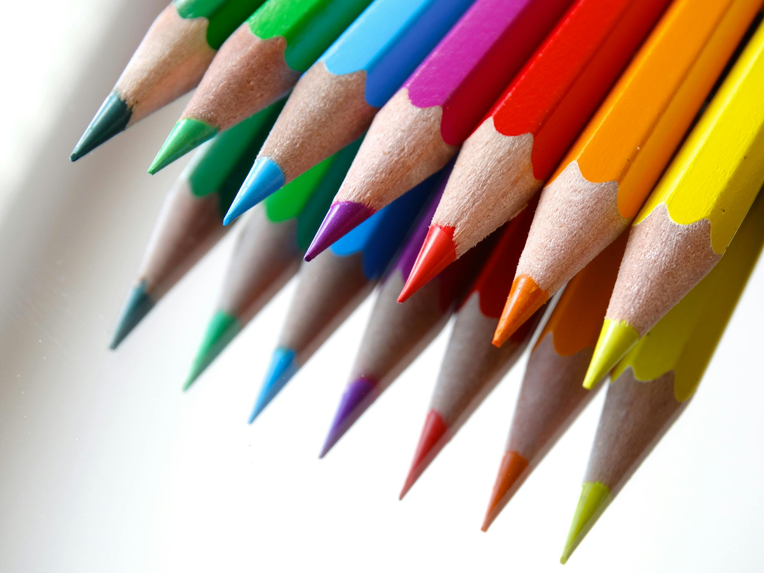 Vibrant colored pencils arranged on a white background, ideal for art and creativity.