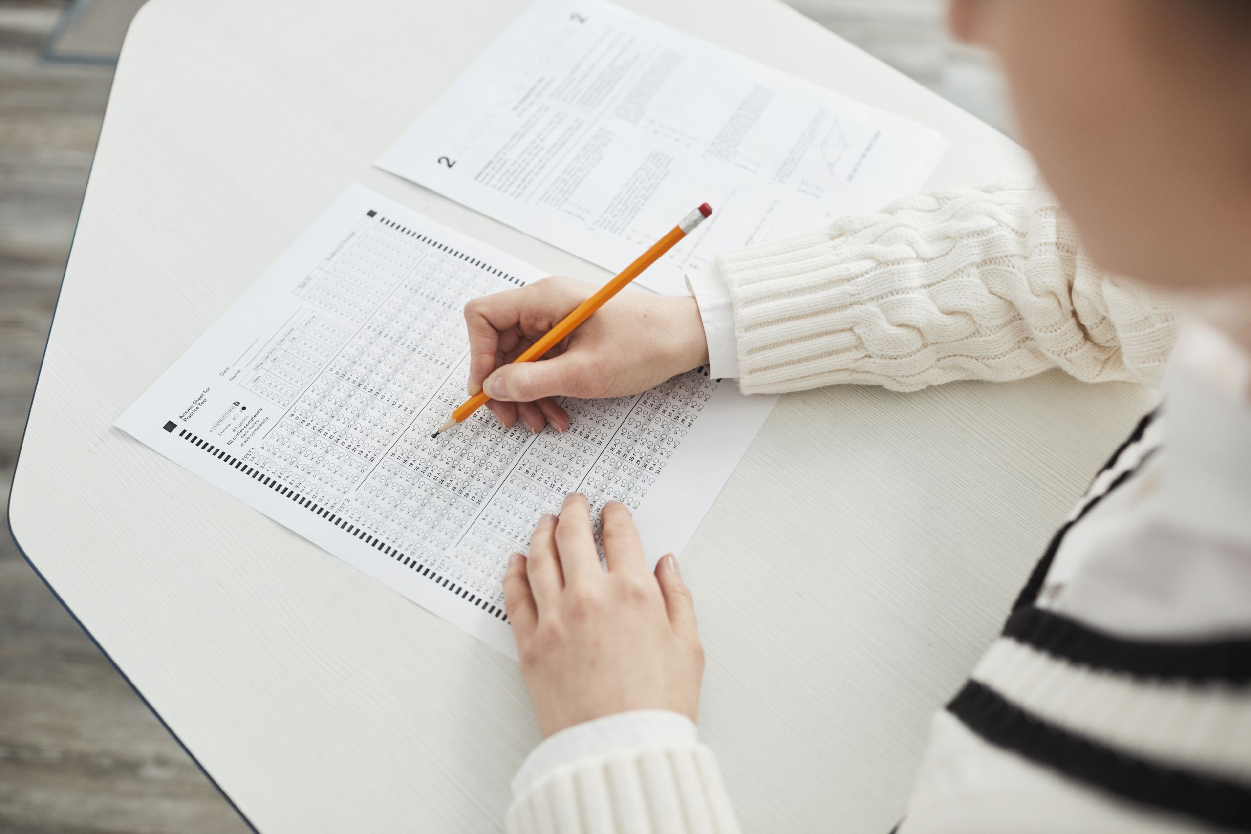 Close-up of a student filling out a multiple-choice exam in a quiet classroom setting.