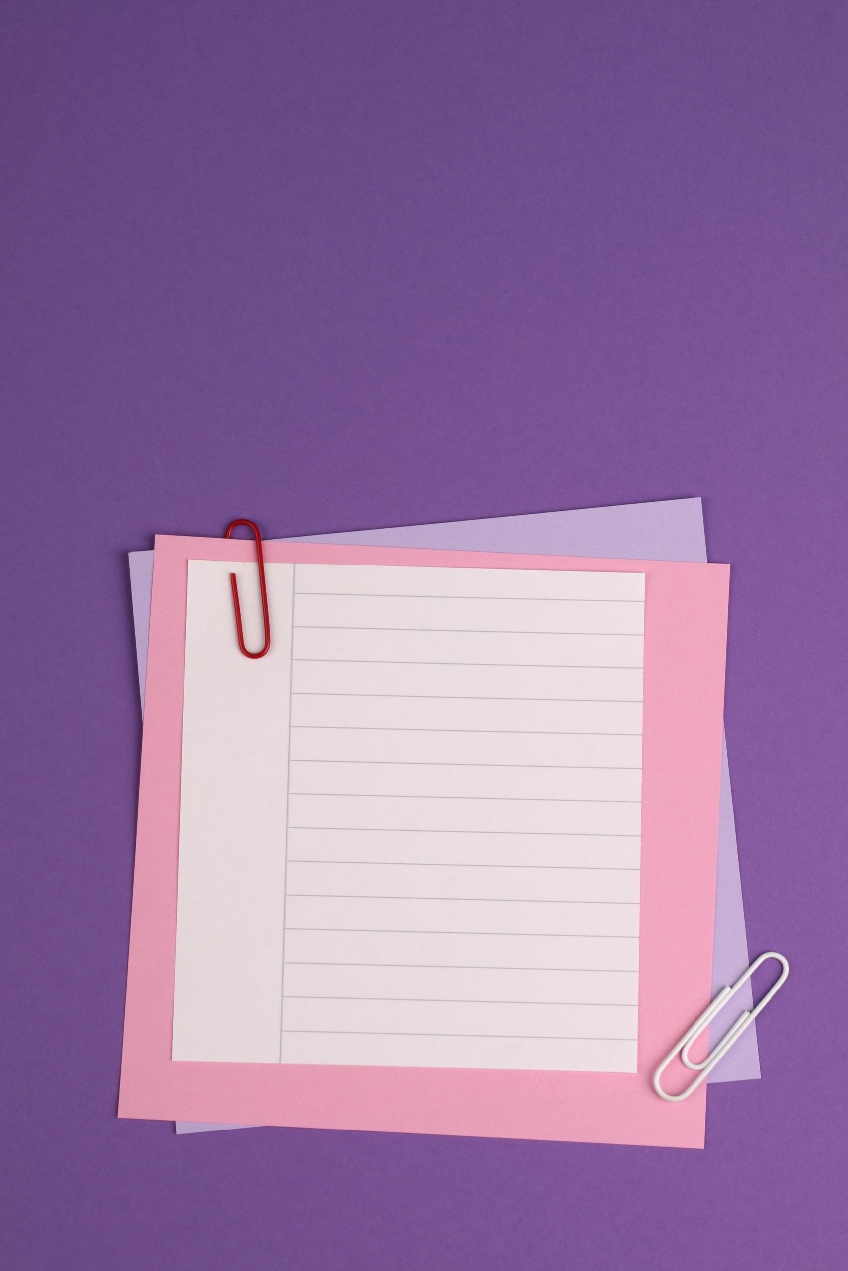 Minimalist still life of paperclips on vibrant purple background with pastel papers.